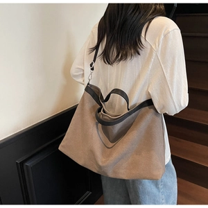 Close-up of a large khaki canvas tote bag with black contrast straps and silver hardware