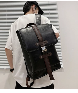 Close-up of black PU leather backpack featuring brown straps and litchi grain texture