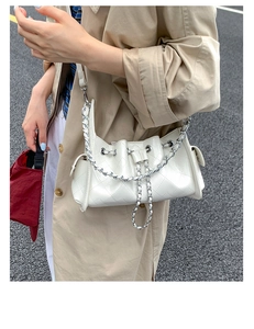 Détail du sac seau matelassé blanc avec chaîne argentée et finition en cuir verni brillant