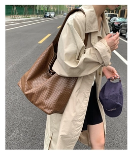 Detail of the brown woven tote bag featuring an intricate square weave texture and large capacity