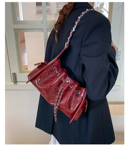 Détail du sac bandoulière matelassé rouge foncé avec finition brillante et chaîne argentée