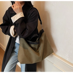 Detailed close-up of large canvas tote bag in olive green with black contrast straps