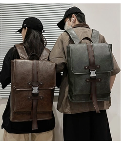 Rear view of couple wearing vintage leather backpacks in dark brown and forest green