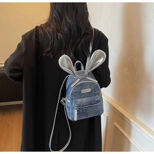 Detail view of blue denim mini backpack featuring glitter finish and silver bunny ears