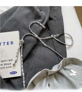 Detailed macro view of silver ruched cloud bag with metallic butterfly charm and chain strap