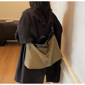 Detail view of large canvas tote bag with contrast strap shown on model's shoulder