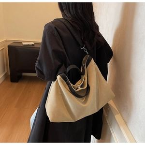 Detail of a large canvas tote bag showing detachable black shoulder strap and top handles