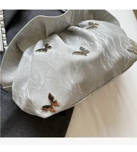 Close-up of silver pleated cloud bag with metallic texture and butterfly charms