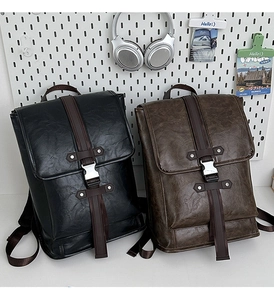 Close-up of black and brown vintage PU leather backpacks with metal buckles and straps