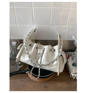 Détail du sac bandoulière en cuir blanc matelassé avec chaîne argentée et poches latérales