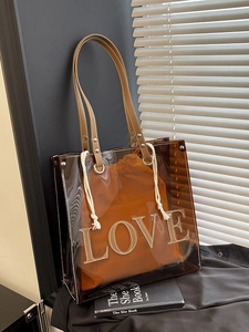 Transparente PVC-Tragetasche mit braunem Innenbeutel und LOVE-Patchwork-Design im Studio