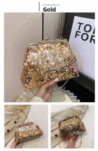 Detail van een gouden avondtas met pailletten, strasbloemen en een metalen ketting