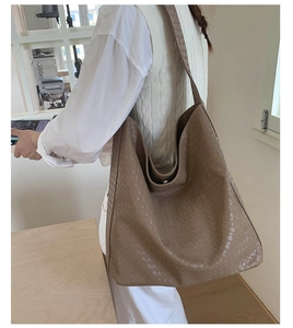 Detail of dark brown hobo tote bag featuring intricate woven leather texture and magnetic closure