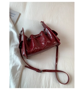 Détail de la texture en cuir matelassé bordeaux et du cordon de serrage du sac