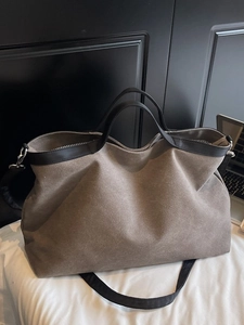 Large brown canvas tote bag with black trim and adjustable shoulder strap for travel