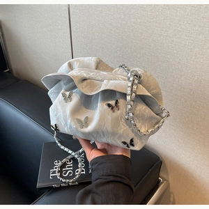 Detailed view of grey pleated cloud bag with silver butterfly charms and chain strap