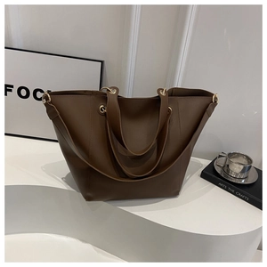 Detail of a brown leather bucket bag with wide shoulder strap and gold eyelets