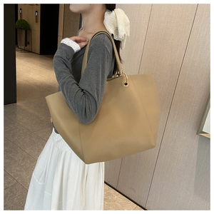 Khaki faux leather tote bag with gold ring detail worn by a model in a modern office