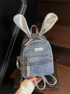 Vintage blue denim backpack with silver rabbit ears and fashion label shown in hand