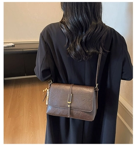 Détail d'un sac bandoulière vintage en cuir marron avec boucle en métal et breloque