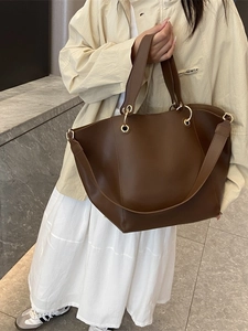 Retro brown bucket tote bag with gold ring hardware shown as a shoulder bag on a model