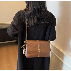 Vue arrière du modèle portant un sac bandoulière vintage marron avec perles en bois