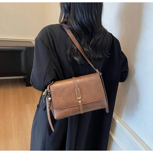Petit sac carré marron rétro avec boucle dorée et gland perlé porté par un mannequin