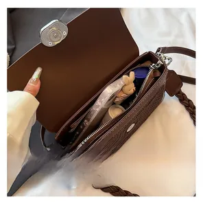 Detail of woven brown leather crossbody bag interior showing phone and lipstick storage