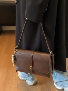 Petit sac carré marron rétro avec boucle dorée et charm perlé porté par un modèle