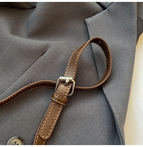 Detail of dark brown lychee leather strap with yellow stitching and silver buckle