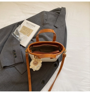 Detail view of two-tone bucket bag interior with zipper pocket and plush sheep charm