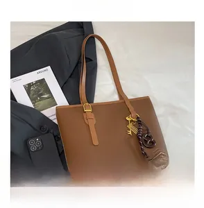 Detail view of brown lychee grain leather tote with gold hardware and creative charms