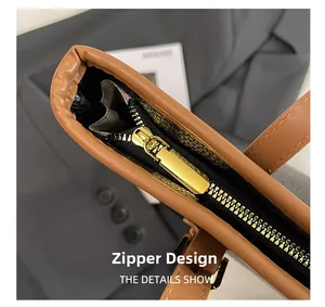 Close-up of golden zipper on a brown pebble leather tote bag with elegant metal hardware
