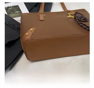 Detail of brown leather tote bag showing precision stitching and gold hardware accents