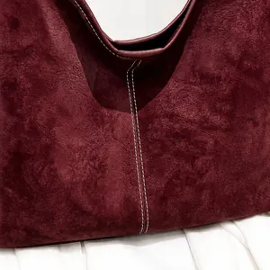Detalle del bolso tote burdeos en ante sintético con costuras blancas en contraste