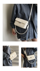 Detailed view of beige crossbody bag with woven texture and silver oval metal buckle