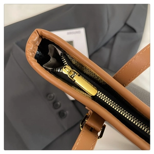 Detail of premium brown leather tote bag with gold zipper and adjustable buckle strap
