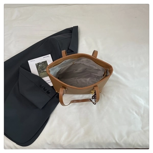 Detail of large brown pebble leather tote bag with silk scarf and metal horse charm