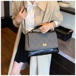 Detail of grey suede and black leather crossbody bag with quilted stitching and gold lock