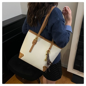 Detailed side view of off-white and brown leather tote bag on model in modern setting