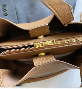 Detailed close-up of brown litchi pattern leather with smooth golden metal zipper hardware
