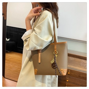 Detail of contrast stitch tote bag with gold studs and a woven keychain accessory