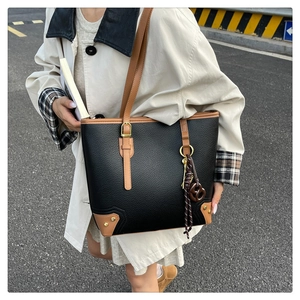 Detail of large black leather tote bag with brown straps and textured pebble grain finish