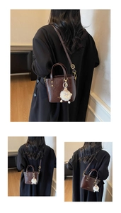 Detail of dark brown leather bucket bag with gold lettering and white sheep charm pendant