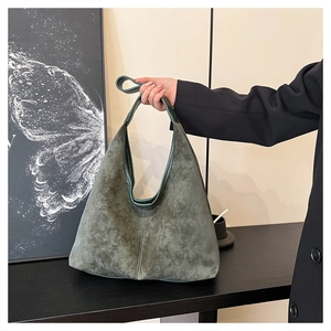 Detalle de bolso hobo grande en ante verde oscuro con costuras en contraste y asa robusta