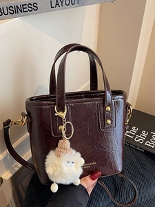 Fashionable burgundy bucket tote bag in wrinkled leather with a cute plush monster charm