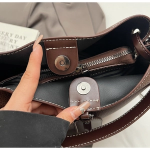 Macro detail of dark brown bucket bag with lychee grain leather and double magnetic closures
