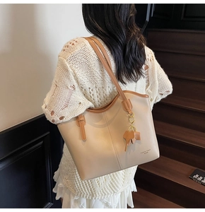 Close-up of beige tote bag with brown straps and a cute elephant charm pendant