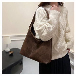 Detalle de un bolso hobo grande de ante marrón con costuras en una modelo mujer