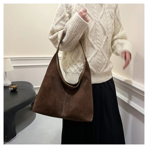 Detalle del bolso tote marrón oscuro en cuero mate con costuras verticales blancas